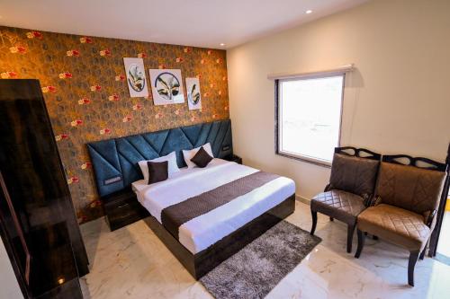 a bedroom with a bed and a window and a chair at Madhuram Hotel in Ayodhya