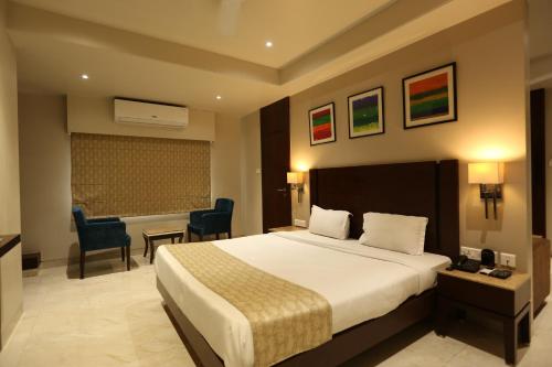 a hotel room with a bed and a desk and chairs at PRAGATI MANOR in Guwahati