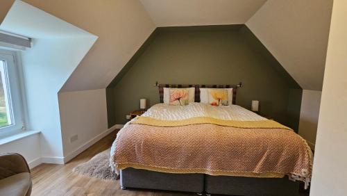 a bedroom with a large bed in the attic at Donmar Cottage in Skeabost