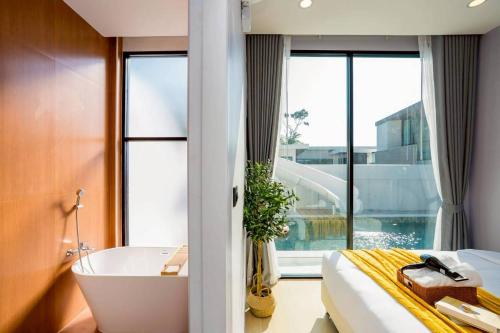 a bedroom with a tub and a bed and a window at Cloud Pool Villa Pattaya in Na Jomtien
