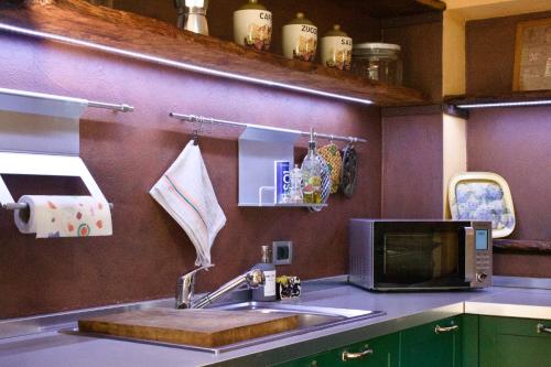 a kitchen with a sink and a microwave at Tra le Alpi - Holiday House in Tresivio