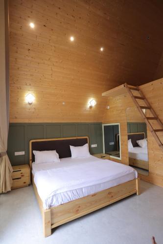 a bedroom with a large bed in a wooden room at Alpine Vista Wellness & Resort in Gupta Kāshi