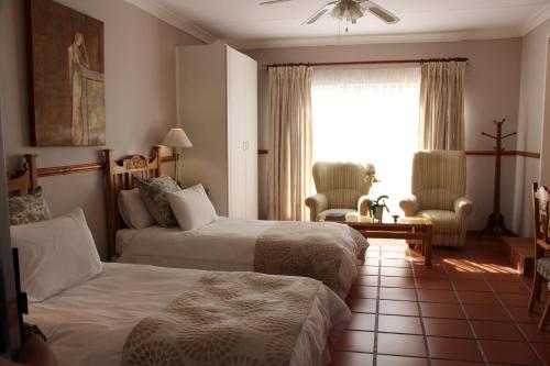 a hotel room with two beds and a window at Chez Esme Guest House in Roodepoort