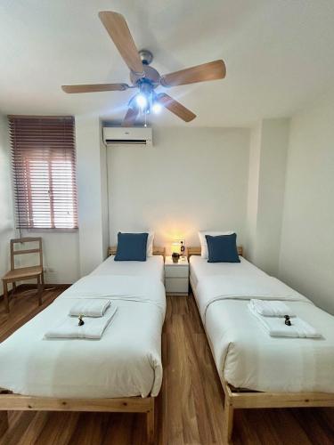 two beds in a room with a ceiling fan at GATU City Puerto Preferente mayores 21 años y familias in El Puerto de Santa María