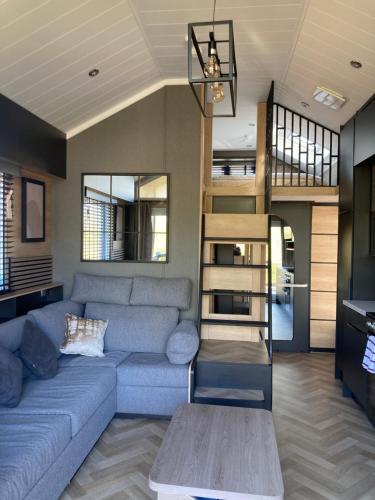 a living room with a blue couch and a staircase at Chapel Fields Holiday Park in Chapel Saint Leonards