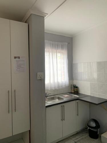a kitchen with white cabinets and a sink and a window at Let Us accommodation in East London