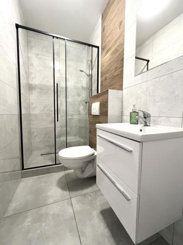 a white bathroom with a toilet and a shower at Domki Selma in Władysławowo