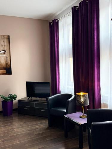 a living room with purple curtains and a television at Harmonica Studio in Nowy Sącz