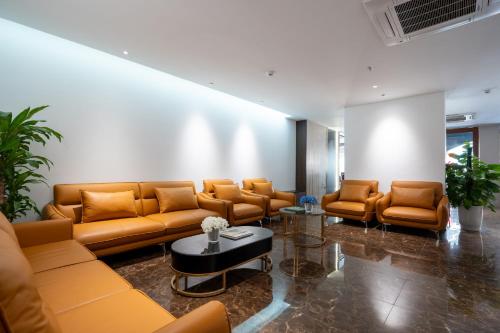 a waiting room with brown leather couches and a table at Luxe Paradise Hotel Truc Bach in Hanoi