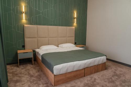 a bedroom with a large bed with a green wall at Nord Karakol Hotel in Karakol