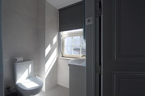 a bathroom with a toilet and a sink and a window at Santiago de Caminha Boutique Hostel & Suites in Caminha