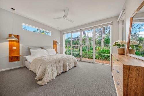 a bedroom with a bed and a large window at Three Pines on Grange in Porepunkah