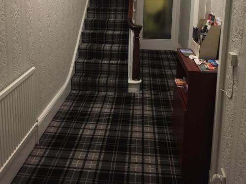 a hallway with a staircase with a plaid tile floor at Richmond House Hotel in Southport