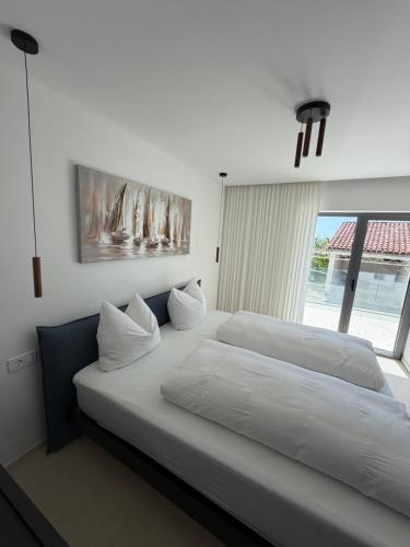 a large bed in a bedroom with a large window at Villa Čapula - Modern Apartment with Sea View and Parking, Marušići in Omiš