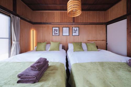 two beds in a room with wooden walls and windows at Neuk Nakanosima in Ikuta