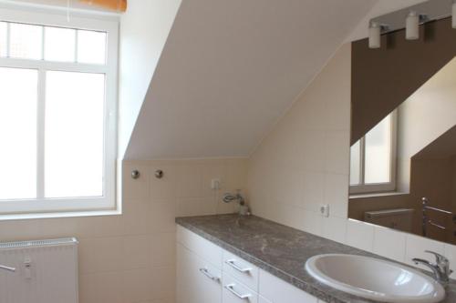 a bathroom with a sink and a large mirror at Ferienwohnung in der Villa Seestern in Nienhagen