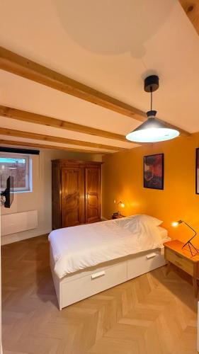 a bedroom with a large white bed and yellow walls at La petite maison orange in Koenigsmacker