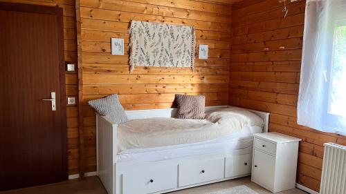a bedroom with a white bed in a wooden wall at Ferienhaus Waldliebe in Grafenau