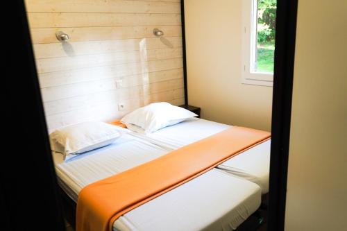 a bedroom with a bed with an orange and white blanket at Les Buissonnets in Saint-Georges-de-Didonne