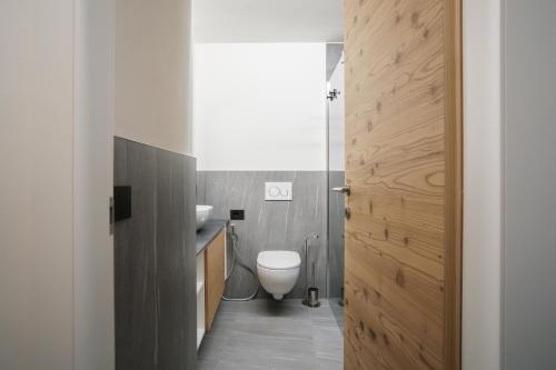 a bathroom with a toilet and a sink and a door at Casa Bepa in Bormio