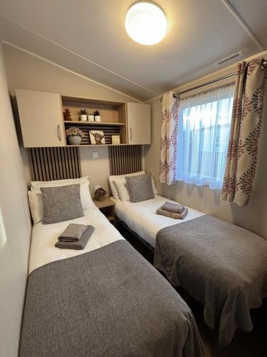 two beds in a small room with a window at Dulce Casa 34 2 bedroom with hot tub in Grantown on Spey