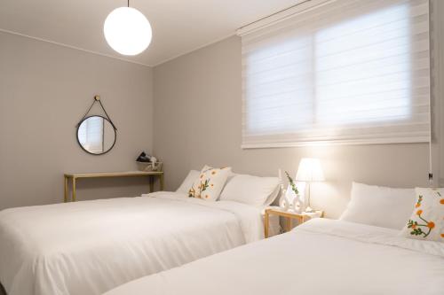 zwei weiße Betten in einem Zimmer mit Fenster in der Unterkunft 스테이솜 in Daejeon