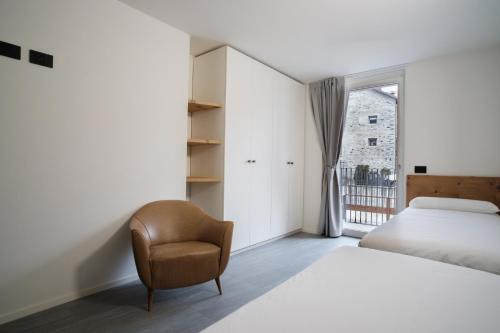 a bedroom with a bed and a chair and a window at Casa Bepa in Bormio