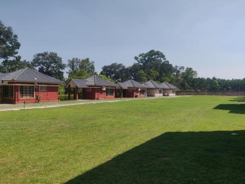 a row of houses with a large grass field at Dubare Inn Coorg in Siddapur