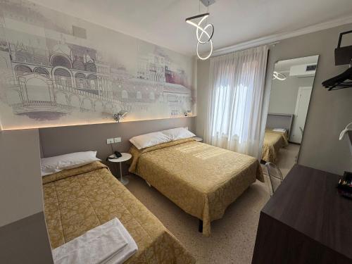 a bedroom with two beds and a painting on the wall at Hotel Adriatico in Venice