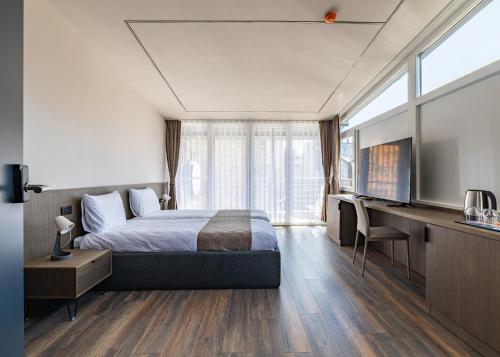 a bedroom with a bed and a desk and a television at Four Side Hotel in Prishtinë