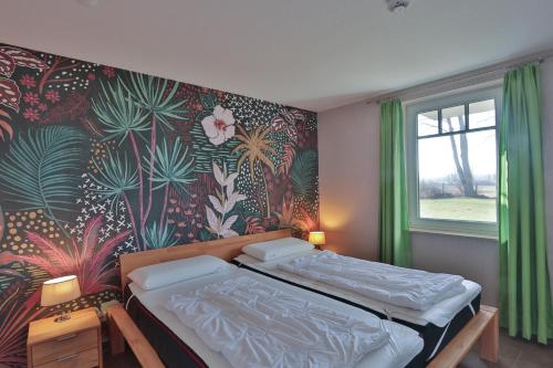 a bedroom with a bed with a tropical wallpaper at Sommersprosse in Börgerende-Rethwisch