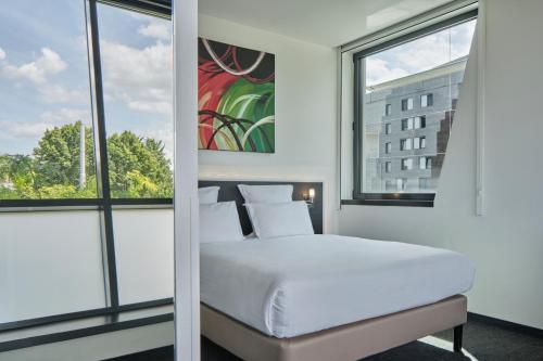 a bedroom with a white bed and two windows at Hôtel Restaurant Athena Spa in Strasbourg