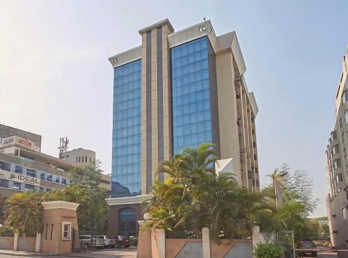 a tall building with palm trees in front of it at Hotel Studio Estique in Pune