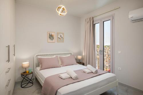 a white bedroom with a large bed with pink pillows at Kamara View Apt 2 in Agios Nikolaos