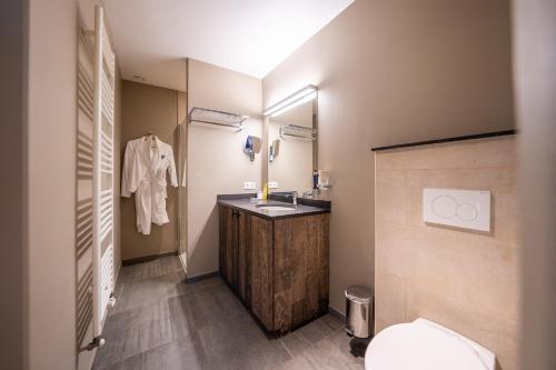 a bathroom with a sink and a toilet and a mirror at La Barrière de Transinne in Libin