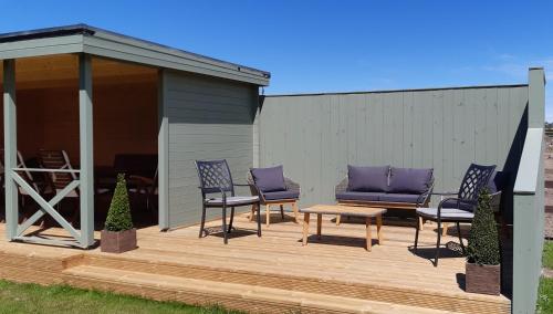 a deck with chairs and a bench and a gazebo at Eirianfa in Menai Bridge