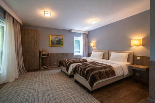 a bedroom with two beds and a window at La Barrière de Transinne in Libin