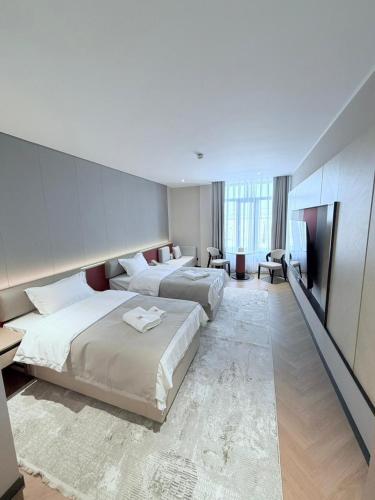 a hotel room with two beds and a television at AQMYRZA Inn in Zharkent