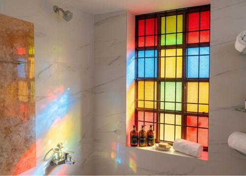 a bathroom with a rainbow stained glass window at Amma Stays and Trails in Kotikulam