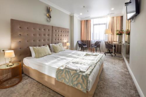 a bedroom with a large bed with a large headboard at Bristol Central Park Hotel in Chişinău