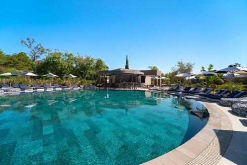 a large swimming pool with chairs and umbrellas at Cabú Hotel Adults Only - Small Luxury Hotels of the World in Faliraki