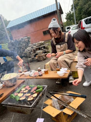 a group of people cooking food on a grill at 静かな森の古民家ステイ Tunagiつなぎ in Nishiwaga