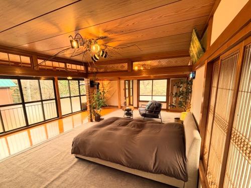 a bedroom with a large bed in a room with windows at 静かな森の古民家ステイ Tunagiつなぎ in Nishiwaga