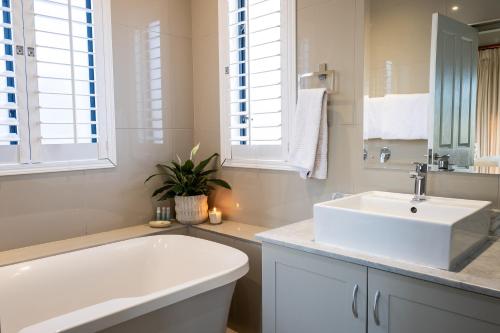 a white bathroom with a sink and a tub at Gowrie Farm Golf Lodge in Nottingham Road