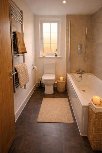 a bathroom with a toilet and a tub and a window at Beautiful Modern Home in Wisbech with Private Garden in Wisbech Saint Mary