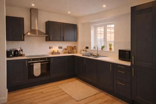 a kitchen with black cabinets and a sink at Beautiful Modern Home in Wisbech with Private Garden in Wisbech Saint Mary