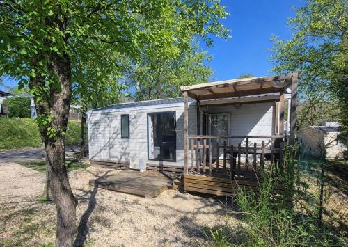 a tiny house with a porch and a tree at The Mobil home Confort Clim / 2 Chb / 5 Pers in Lagorce