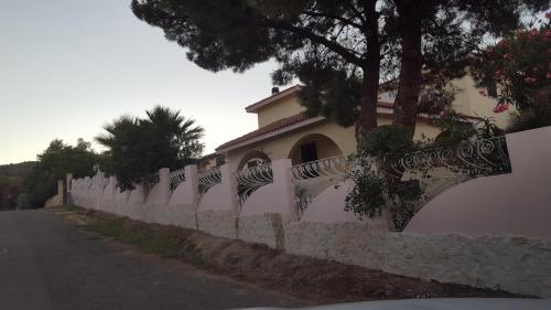 a white fence with trees on the side of a building at Borgo degli Ulivi Depandance in Capoterra