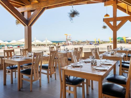 ein Restaurant mit Holztischen und Stühlen und der Strand in der Unterkunft Hotel Cerna in Saturn