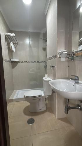 a white bathroom with a toilet and a sink at Hostal Victoria Mar in Chipiona